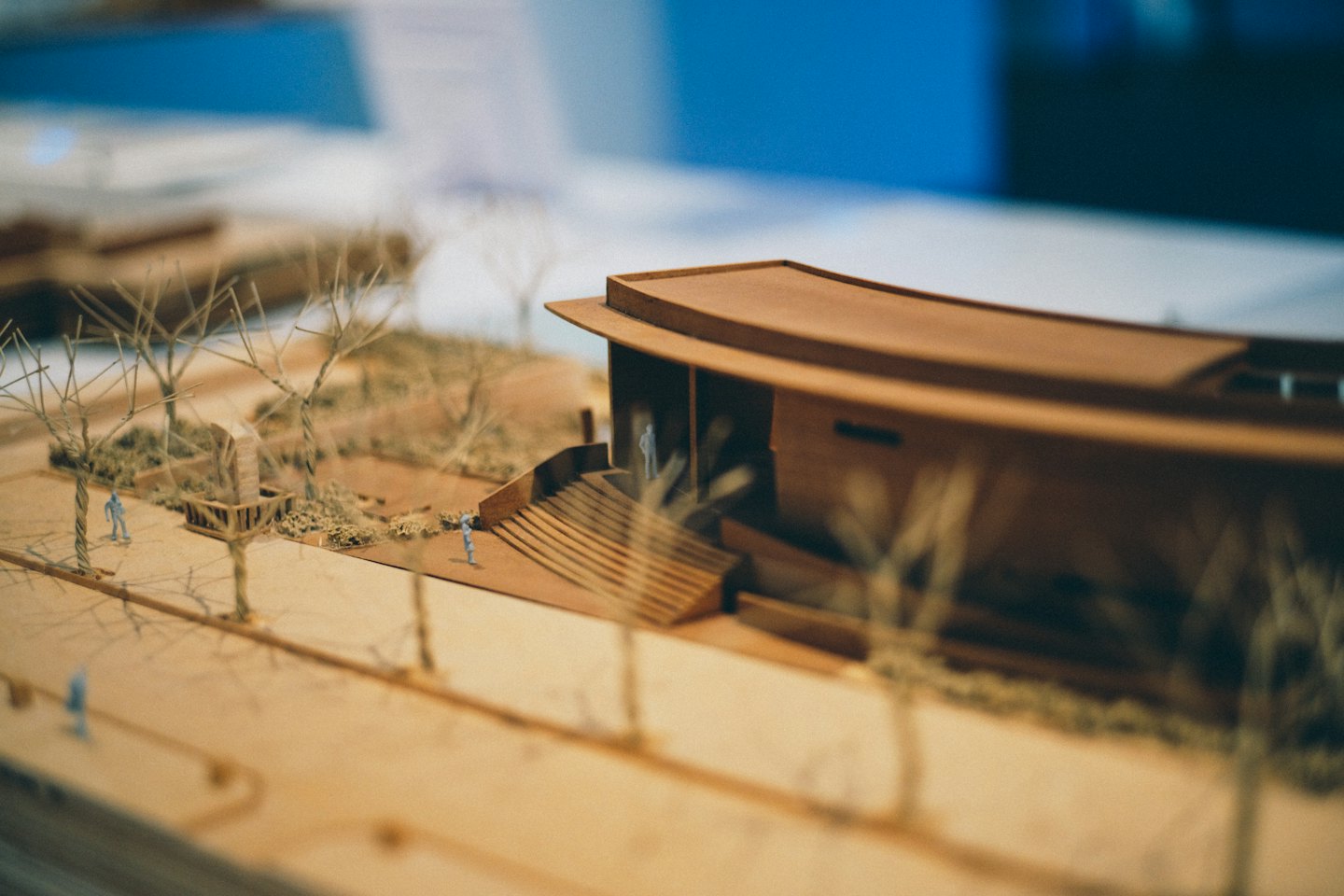 Architectuurmodel van een modern gebouw met gebogen dak en miniatuurlandschap.